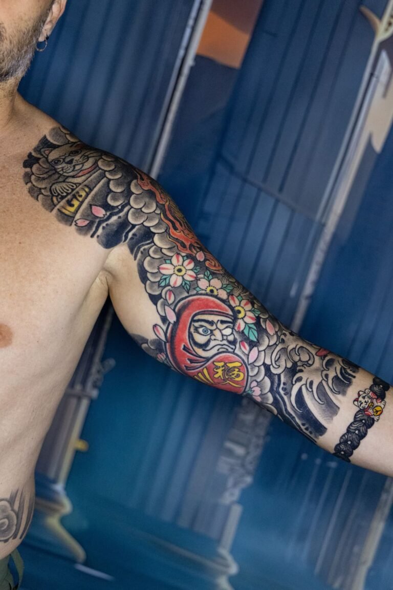 Antebrazo con daruma y motivos japoneses a color, manga curada por Kabra en Museum Tattoo Valencia