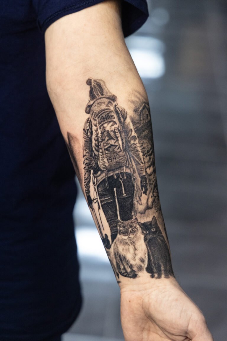Tatuaje realista de montañero con mochila y dos gatos en el antebrazo, por Paco Serra – Museum Tattoo Valencia